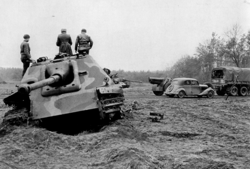 Советский офицер осматривает подбитую в Восточной Пруссии немецкую САУ «Ягдпантера» (Sd.Kfz.173 Jagdpanther). Справа — штабная машина у грузовика артиллеристов с 122-мм гаубицей образца 1910/30 годов, на дальнем плане подбитый советский танк ИС-2