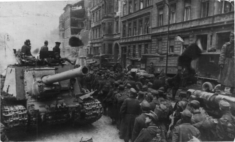 Колонна немецких военнопленных проходит мимо советских самоходных артиллерийских установок ИСУ-122 по улице Берлина
