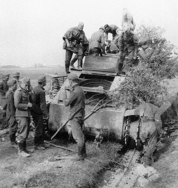 Немецкие солдаты осматривают потерявший гусеницу и брошенный экипажем Т-28 из состава 5-й танковой дивизии 3-го мехкорпуса. Северо-Западный фронт, район Алитуса, июнь 1941 года (АСКМ).