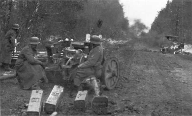 Расчет 50-мм противотанковой пушки Pak 38 на огневой позиции. Октябрь 1941 года, полоса наступления 2-й танковой группы. На переднем плане видны ящики для укладки 50-мм выстрелов (по 4 штуки в каждом), на дороге горит советский грузовик ГАЗ-АА (РГАКФД).