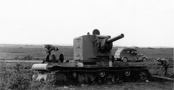 Немецкие офицеры осматривают танк КВ-2 из состава 2-й танковой дивизии 3-го мехкорпуса. Литва, июнь 1941 года. Скорее всего, машина застряла и была оставлена экипажем после неудачных попыток её вытащить — перед гусеницами лежит бревно. На надгусеничной полке стоит 152-мм снаряд и заряд (АСКМ).