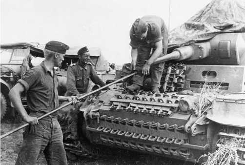 Экипаж танка Pz.III Ausf.F 16-й <a href='https://arsenal-info.ru/b/book/1627328415/38' target='_self'>танковой дивизии</a> за чисткой орудия. 1941 год. Машина прошла значительную модернизацию, в ходе которой на ней установлена 50-мм пушка, усилено бронирование лобового листа подбашенной коробки и верхнего и нижнего лобовых листов корпуса. Несмотря на это экипаж, где только можно, навесил на машину гусеничные траки.