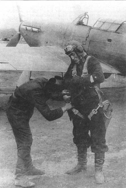 Механик помогает старшему лейтенанту П.И. Сгибневу застегнуть парашют, 1942 год. Сбигнев служил в авиации Северного флота. В 1942 году он довел свой боевой счет до 19 побед и стал командиром 2-го ГвИАП после гибели Сафонова.