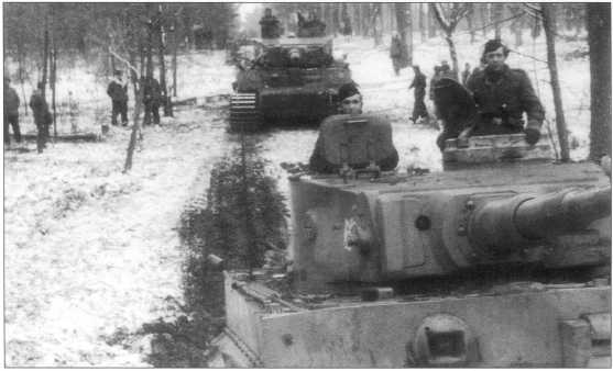 Танки «Тигр I» передвигаются на новые позиции. Машины окрашены в базовый Dunkel Gelb, с нанесенным на него коричневым камуфляжем. На башне видна белая символика с изображением гнома. Советско-германский фронт, конец 1943 года.