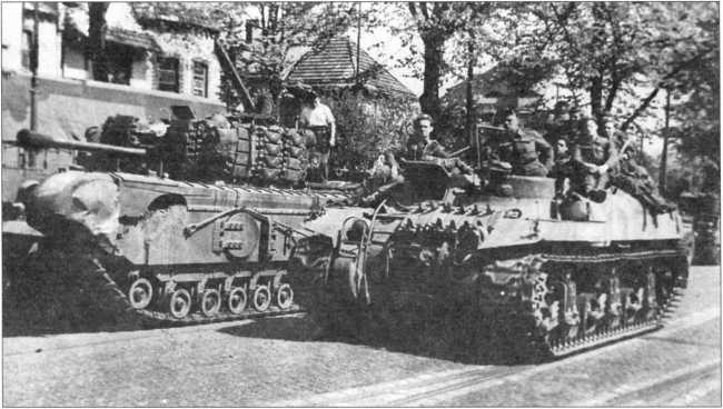 Бронетранспортер Ram Kangaroo проезжает мимо пехотного танка Churchill по улице бельгийского городка. 1944 год.