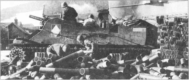 М7 из состава 5-й французской танковой дивизии на огневой позиции. Франция, декабрь 1944 года. На переднем плане — картонные пеналы для транспортировки 105-мм унитарных выстрелов.