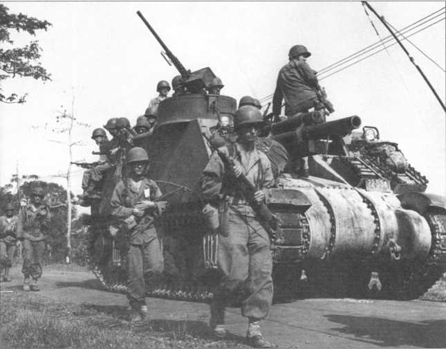 Пехотинцы 33-й американской пехотной дивизии и САУ М7 из состава 130-й артиллерийской роты на о. Лусон, Филиппины, март 1945 года.