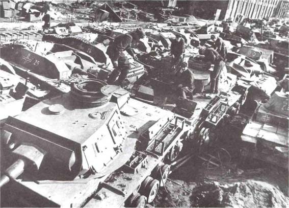 Ремонтники осматривают танки Pz. III, на переднем плане танк Pz. III из состава 18-й <a href='https://arsenal-info.ru/b/book/1627328415/38' target='_self'>танковой дивизии</a> немцев, оснащённый оборудованием для подводного хода. Москва, рембаза № 82, апрель 1942 года (АСКМ).