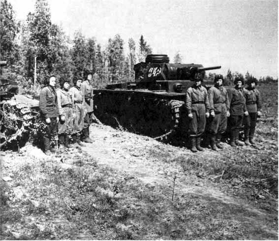 Командиры танков 107-го отдельного танкового батальона уточняют боевую задачу. Волховский фронт, 6 июля 1942 года. На заднем плане танки Pz. IV и Pz. III с экипажами (РГАКФД).