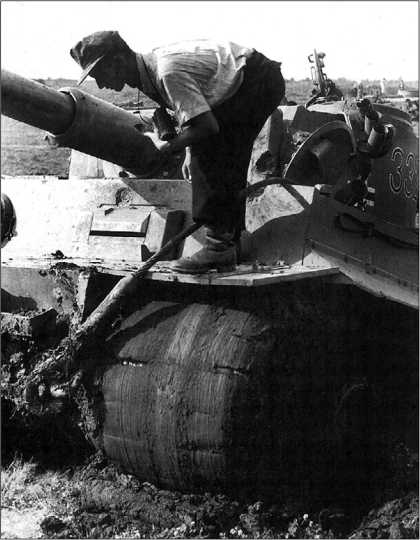 Не только мосты, но и проселочные дороги России не всегда выдерживали большую массу немецкого тяжелого танка, что порой весьма существенно затрудняло маневрирование. На фото вверху и внизу — безнадежно застрявший в грязи «Тигр» № 332 из 503-го тяжелого танкового батальона. На лобовой броне корпуса, маске пушки и на ее стволе хорошо видны отметины от попаданий советских снарядов. Курская дуга, июль 1943 года.