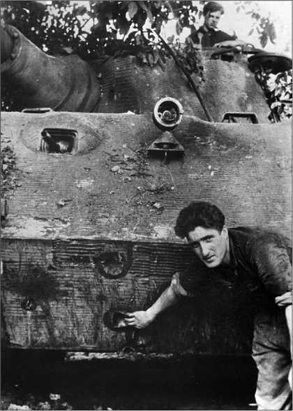 Немецкий танкист демонстрирует вмятины на нижнем лобовом листе корпуса «Королевского тигра». 75-мм английские и американские снаряды не причиняли этому танку никакого вреда.