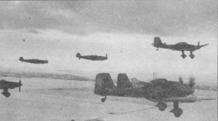 Звено Ju-87D-5 направляется на боевое задание под эскортом двух истребителей B/.109G. Юнкерсы имеют временную зимнюю окраску. К моменту принятия на вооружение люфтваффе Ju-87D-5, яркие эмблемы подразделений на бортах немецких самолетов уже остались в прошлом. Маркировка ограничивалась полосами театра военных действий и буквенно-цифровым бортовым идентификационным кодом.
