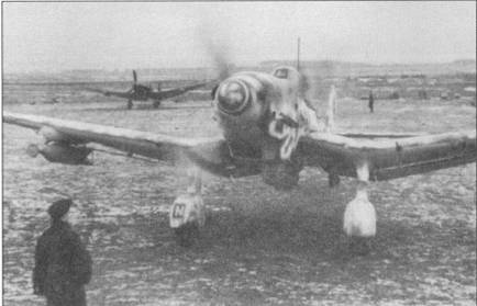 Ju-87D-5 в «змеином» камуфляже выруливает на старт, зима 1943-44 г.г. Под плоскостью крыла подвешена бомба SC-250, под фюзеляжем — контейнер АВ- 500 с <a href='https://arsenal-info.ru/b/book/2633435995/27' target='_self'>осколочными боеприпасами</a>.