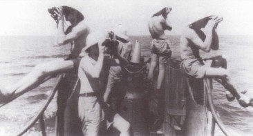 Фото: Вахтенный офицер и четверо моряков наблюдают за водой и воздухом. На головы одеты тропические шлемы, что весьма необычно. Жара стоит в тропических водах. Рубашки сняты, оставлены только шорты.
